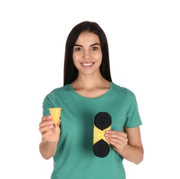 Young woman with menstrual cup and reusable pad on white background