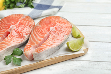 Fresh raw salmon with parsley and lime on white wooden table. Fish delicacy