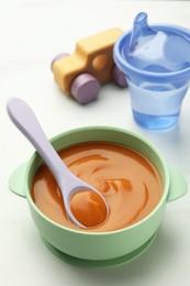 Bowl and spoon with tasty pureed baby food on white table