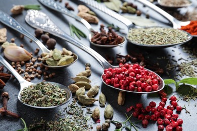 Different natural spices and herbs on black table, closeup
