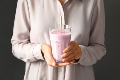 Woman holding fig smoothie on grey background, closeup