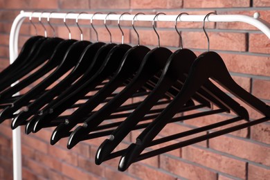 Black clothes hangers on rack near red brick wall