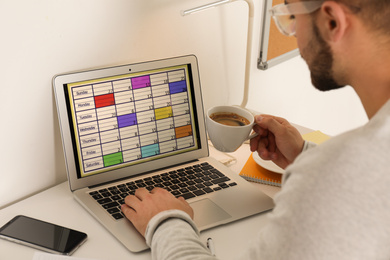 Young man using calendar app on laptop in office, closeup