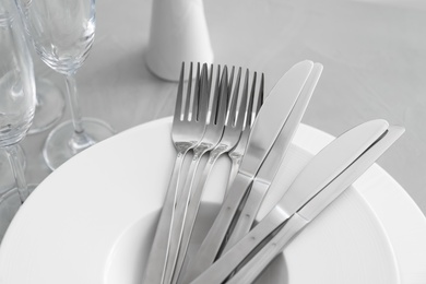 Plates with knives forks on light grey table, closeup