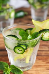 Spicy cocktail with jalapeno, carambola and mint on wooden table, closeup
