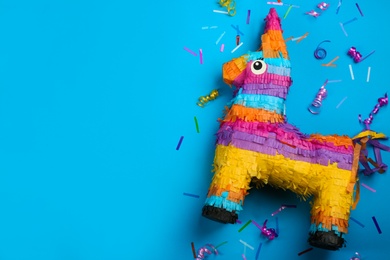 Photo of Llama shaped pinata, streamers and glitter on light blue background, flat lay. Space for text