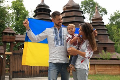 Happy family in national clothes with flag of Ukraine near church