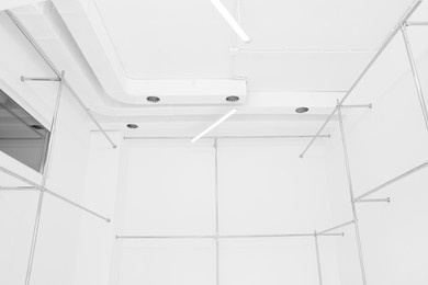 Photo of Empty room with beautiful white walls and garment racks during repair