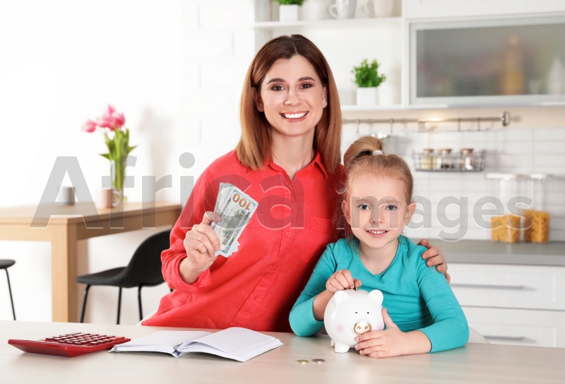 Mother and daughter with money at table in kitchen. Saving money