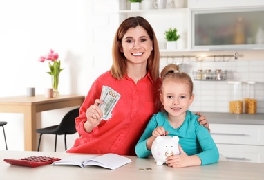 Mother and daughter with money at table in kitchen. Saving money