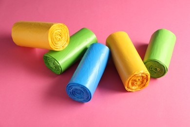 Photo of Rolls of different garbage bags on pink background