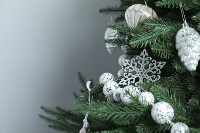 Beautiful Christmas tree with decor on light grey background, closeup. Space for text