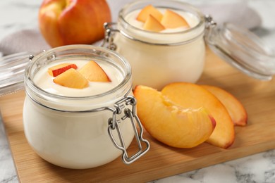 Delicious yogurt with fresh peach on white marble table, closeup