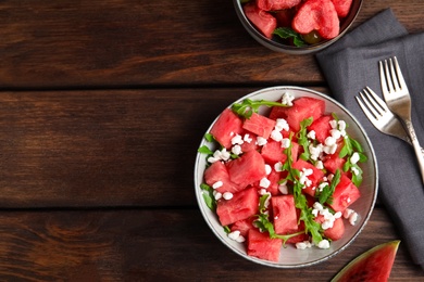 Delicious salad with watermelon, cheese and arugula on wooden table, flat lay. Space for text