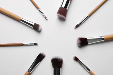 Frame of makeup brushes on white background, flat lay. Space for text