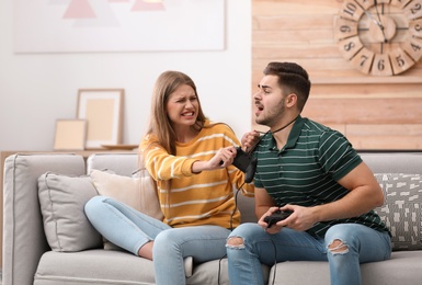 Emotional young couple playing video games at home