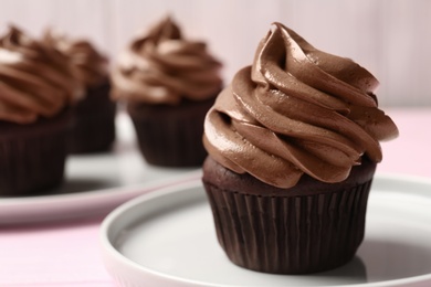 Delicious chocolate cupcake with cream on pink table, closeup