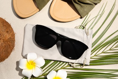 Flat lay composition with stylish sunglasses and cloth bag on sand