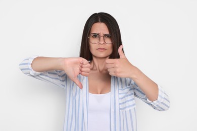 Young woman showing thumbs up and down on white background