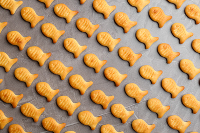 Delicious goldfish crackers on grey table, flat lay
