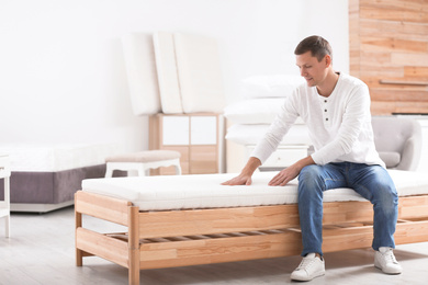 Man touching mattress in furniture store. Space for text