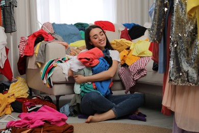 Happy young woman with lots of clothes in room. Fast fashion