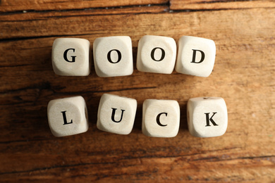 Cubes with phrase GOOD LUCK on wooden table, flat lay