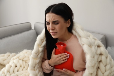Ill woman with hot water bottle suffering from cold at home