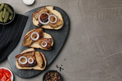Tasty fried pork lard with bread slices and onion on grey table, flat lay. Space for text