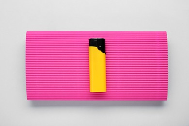 Photo of Stylish small pocket lighter with pink corrugated fiberboard on white background, top view