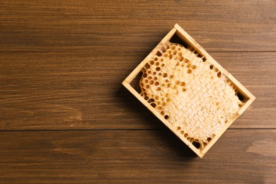 Honeycomb frame on wooden table, top view with space for text. Beekeeping tool