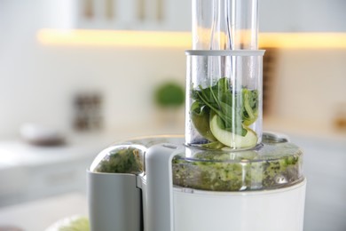 Modern juicer with fresh spinach and fruits in kitchen, closeup