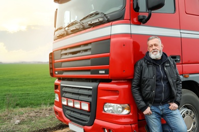 Photo of Portrait of mature driver at modern truck outdoors. Space for text