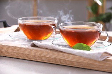 Photo of Aromatic hot tea in glass cups on light grey table indoors, closeup