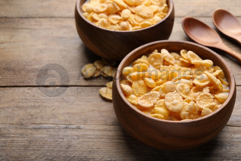 Tasty cornflakes with milk served on wooden table. Space for text