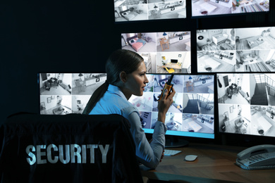 Security guard with portable transmitter monitoring modern CCTV cameras at night