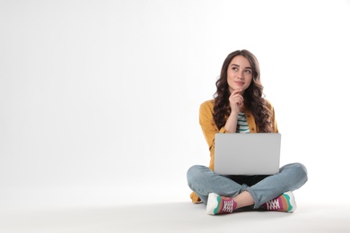Pensive young woman sitting with laptop on white background