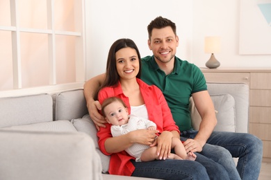Happy couple with adorable baby on sofa at home. Family time
