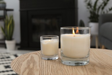 Burning candles in glass holders on wooden table indoors. Space for text