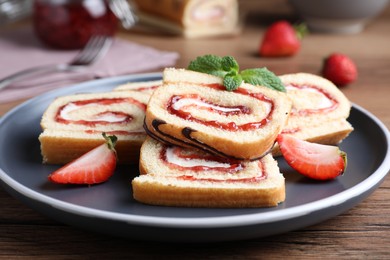 Photo of Tasty cake roll with strawberry jam and cream on wooden table, closeup