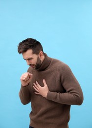 Man coughing on light blue background. Cold symptoms