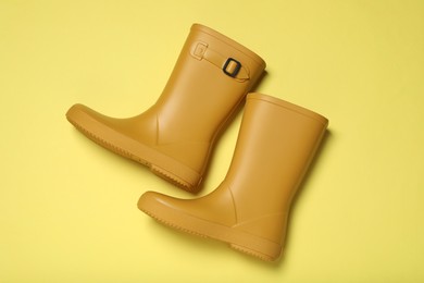 Yellow rubber boots on color background, flat lay