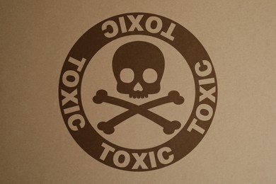 Hazard warning sign (skull-and-crossbones symbol and word TOXIC) on kraft paper, top view