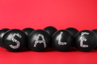Word Sale made of balloons and metallic confetti on red background. Black Friday
