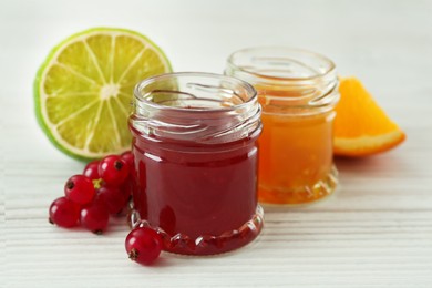 Jars of sweet red currant and citrus jams on white wooden table