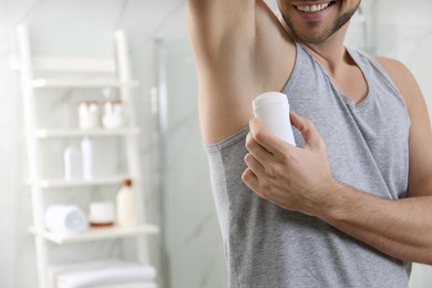 Photo of Man applying deodorant in bathroom, closeup. Space for text
