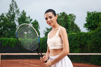 Professional sportswoman with tennis racket at court