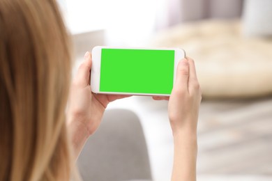 Image of Chroma key compositing. Woman holding smartphone with green screen indoors, closeup. Mockup for design