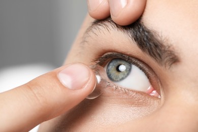 Closeup view of young man putting in contact lens