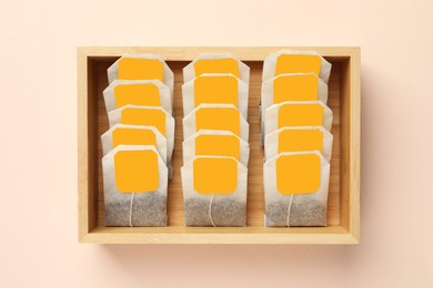 Photo of Many tea bags in wooden box on color background, flat lay
